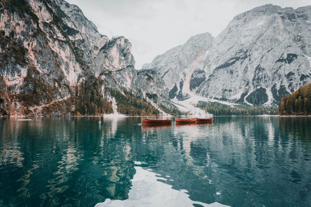 Tranquil lake scene with boats and mountain backdrop in Trentino-Südtirol, Italy.